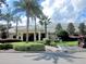 Clubhouse exterior featuring manicured landscaping, palm trees and golf cart parking at 9509 Se 124Th Loop, Summerfield, FL 34491