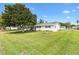 Well-manicured lawn surrounds a charming one-story home with lush landscaping, a cozy porch, and a flagpole at 10385 Se 178Th St, Summerfield, FL 34491