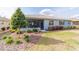 Backyard featuring a screened porch with a ceiling fan, manicured landscaping and green lawn at 10445 Sw 90Th Street Rd, Ocala, FL 34481