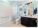 Well-lit bathroom with blue walls, a shower/tub combo, and dark cabinetry with countertop sink at 10445 Sw 90Th Street Rd, Ocala, FL 34481
