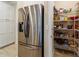 Walk-in pantry with ample shelving and storage space, adjacent to the stainless steel refrigerator at 10445 Sw 90Th Street Rd, Ocala, FL 34481
