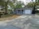 Charming single-story home with blue siding, a one-car garage, and a spacious driveway nestled among mature trees at 10955 Sw 89Th Ave, Ocala, FL 34481