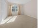 Sunlit bedroom boasts neutral walls, carpeted floor, and window with patterned curtains at 11645 Sw 75Th Cir, Ocala, FL 34476