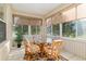 Cozy sunroom features bright windows and comfortable seating around a glass table, perfect for casual dining and relaxation at 13109 Se 86Th Ct, Summerfield, FL 34491