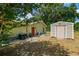 Rear exterior featuring utility sheds, outdoor grill and mature trees on a sunny day at 13300 Ne 38Th Ave, Anthony, FL 32617