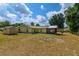 Rear exterior featuring metal shed, green grass and mature trees on a sunny day at 13300 Ne 38Th Ave, Anthony, FL 32617