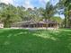 Expansive backyard with lush green lawn, large home, and a screened pool area at 16 Northern Dancer Dr, Ocala, FL 34482