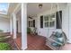 Relaxing front porch featuring a swing, rocking chair, and brick tile flooring at 1910 Se 28Th Pl, Ocala, FL 34471