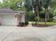 View of the home's pink exterior, white garage door, and concrete driveway lined with mulch and palm trees at 19903 Sw 97Th Ln, Dunnellon, FL 34432