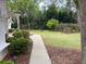 A stone pathway leads through the lush green lawn with a view of the property and mature trees at 19903 Sw 97Th Ln, Dunnellon, FL 34432