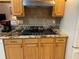 Kitchen cooktop, cabinets, granite countertops, and tile backsplash at 19903 Sw 97Th Ln, Dunnellon, FL 34432