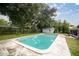 Backyard swimming pool surrounded by a concrete deck, lawn and mature trees on a sunny day at 4516 Ne 8Th St, Ocala, FL 34470