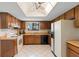 Traditional kitchen with wood cabinets, white appliances, and a ceiling fan skylight at 501 Fairways Ln # A, Ocala, FL 34472