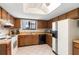 Cozy kitchen featuring wood cabinets, black appliances, white tile floor, and ample sunlight at 501 Fairways Ln # A, Ocala, FL 34472