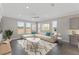 Bright living room featuring a neutral sectional sofa, large windows and a stylish geometric-patterned rug at 5567 Nw 45Th Ln, Ocala, FL 34482