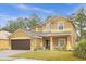 Tan two-story home featuring a large driveway, well-kept lawn, and mature trees at 5781 Sw 39Th St, Ocala, FL 34474