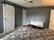 Bedroom featuring light wood floors, modern gray walls, wicker furniture, and a sliding barn door at 6082 Sw 104Th St, Ocala, FL 34476
