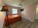 Bedroom features wood-look floors, ceiling fan, lamp, bed, and natural light from a window at 6082 Sw 104Th St, Ocala, FL 34476