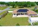 Expansive backyard with green lawn, covered patio, solar panels, storage shed and secure white fence at 6890 Sw 128Th Pl, Ocala, FL 34473