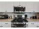 Close-up of a modern gas cooktop with stainless steel microwave and range hood at 6890 Sw 128Th Pl, Ocala, FL 34473