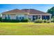 The back of the house with screened patio and well-maintained lawn surrounded by lush greenery at 9172 Se 130Th Loop, Summerfield, FL 34491