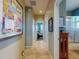 Hallway leads to well-lit bathroom and bedroom, tiled floors, and wall art at 9172 Se 130Th Loop, Summerfield, FL 34491