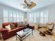 Bright and spacious living room with a ceiling fan, plantation shutters, tile floors, and comfortable furniture at 9172 Se 130Th Loop, Summerfield, FL 34491