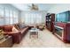 Comfortable living room with a ceiling fan, tile floors, plantation shutters, and a cozy fireplace at 9172 Se 130Th Loop, Summerfield, FL 34491