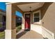 Home's covered front porch featuring a red entry door, classic columns, and elegant lighting fixture at 9856 Sw 100Th Ter, Ocala, FL 34481