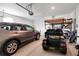Spacious two car garage features a golf cart and a modern car parked with shelving along the wall at 9856 Sw 100Th Ter, Ocala, FL 34481