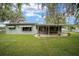 Backyard with a covered patio providing a perfect outdoor space for entertaining, bordered by lush greenery at 12180 Maple St, Dunnellon, FL 34432