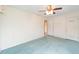 Bright bedroom features neutral walls, plush blue carpeting, and a modern ceiling fan with integrated lighting at 12180 Maple St, Dunnellon, FL 34432