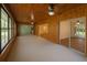 Sunroom with wood paneling, multiple windows, ceiling fans, and views of the property at 12180 Maple St, Dunnellon, FL 34432