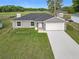 Charming single-story home with an attached garage, set on a lush green lawn against a backdrop of trees at 14914 Se 28Th Ct, Summerfield, FL 34491