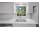 Close up of kitchen sink and window view with white cabinets and tile backsplash at 341 Se 53Rd Ct, Ocala, FL 34480