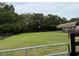 Exterior shot of an open, grassy field with a metal gate and a black wood fence at 6020 Nw 2Nd Ave, Ocala, FL 34475