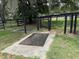 Exterior shot of two dark mats on concrete slabs surrounded by grass and a black wood fence at 6020 Nw 2Nd Ave, Ocala, FL 34475
