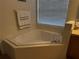 Bright bathroom featuring a tiled platform tub beneath a window with horizontal blinds at 4853 Sw 53Rd Rd, Ocala, FL 34474