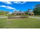 Lovely home featuring lush landscaping, a sprawling lawn, and charming architectural details under a bright blue sky at 5950 Sw 21St Avenue Rd, Ocala, FL 34471