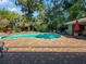 Backyard view of a sparkling swimming pool, patio, pergola, and lush landscaping at 4085 Se 23Rd Ter, Ocala, FL 34480