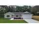 Charming single-story home with a gray exterior, a well-manicured lawn, and an attached two-car garage at 27 Juniper Pass Way, Ocala, FL 34480