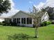 Rear view of home showing screened porch, lush lawn, and mature landscaping at 11495 Sw 138Th Ln, Dunnellon, FL 34432