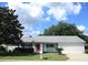 Charming single-story home featuring a well-maintained lawn, mature trees, and an inviting red front door at 11495 Sw 138Th Ln, Dunnellon, FL 34432