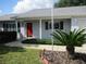 Inviting front entrance with a red door, well-manicured landscaping, and a quaint walkway to the house at 11495 Sw 138Th Ln, Dunnellon, FL 34432