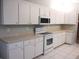 Bright kitchen with white appliances, white cabinets and tile flooring at 11495 Sw 138Th Ln, Dunnellon, FL 34432