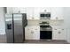 Close-up view of the kitchen's stainless steel appliances and sleek white cabinetry at 11555 Sw 59Th Ter, Ocala, FL 34476