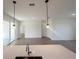 Open-concept living space with an island kitchen, sliding glass doors, and modern pendant lighting at 11555 Sw 59Th Ter, Ocala, FL 34476