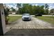View of the driveway with a parked silver minivan and black Tesla, plus a front lawn with mature trees at 15115 Se 94Th Ct, Summerfield, FL 34491