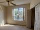 Bright bedroom with neutral carpet, a ceiling fan, and a large window providing natural light at 1703 Sanderling St, The Villages, FL 32162