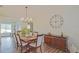 Elegant dining room with a modern chandelier, hardwood floors and a large clock on the wall at 17475 Se 107Th Ct, Summerfield, FL 34491